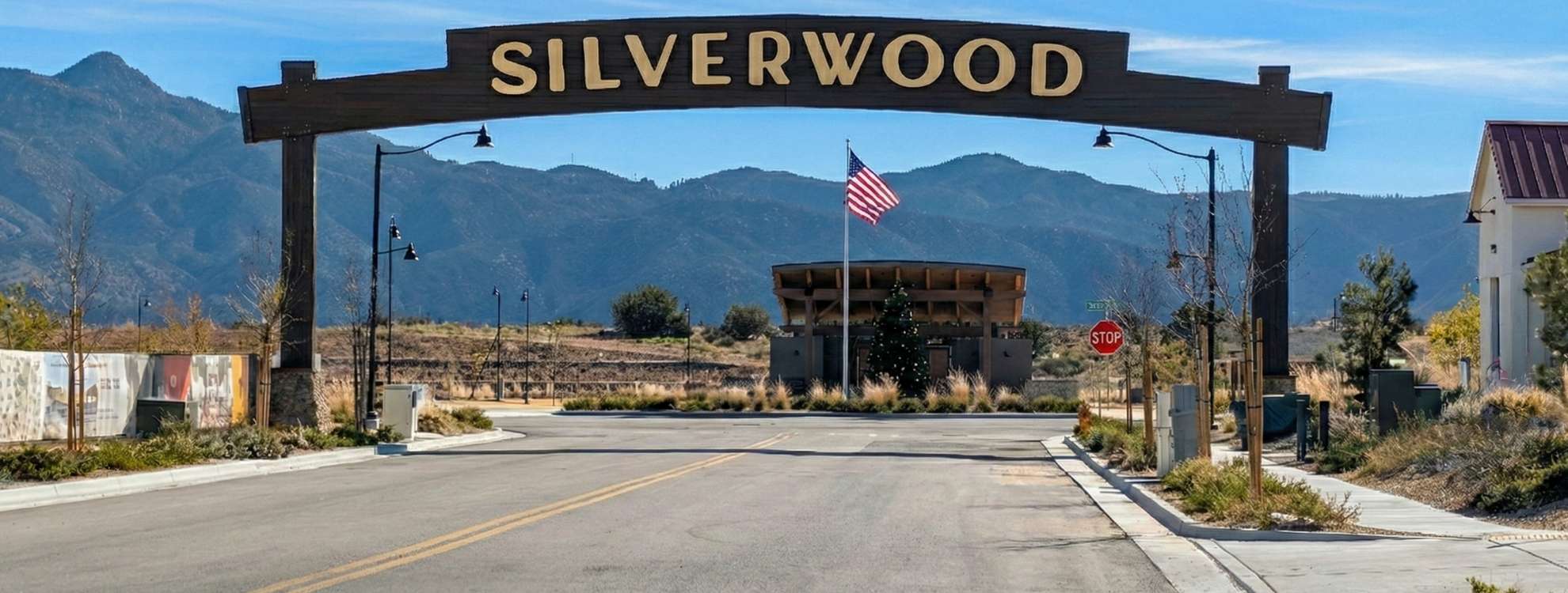 Large wooden entrance arch with 'SILVERWOOD' in gold letters, framing a new master-planned community and mountain range in Hesperia, CA.
